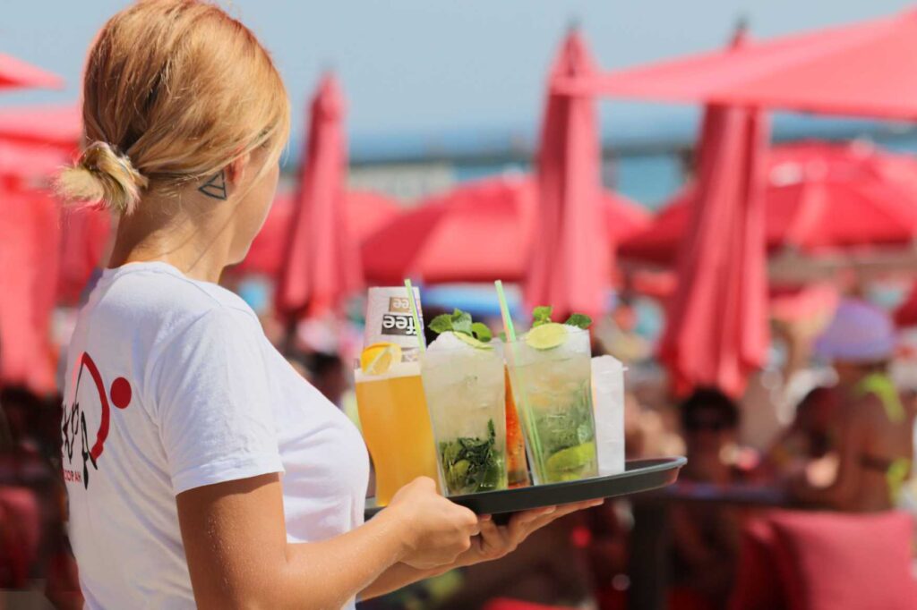 Servírka obsluhující hosty během sezónní práce v turistickém letovisku v Řecku