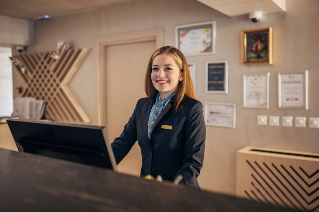 Recepční pracující v hotelu v Dánsku během obsluhy hostů.