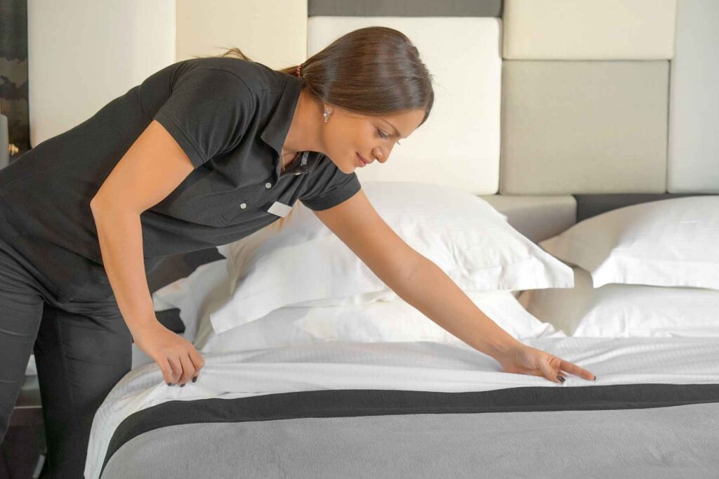 Pracovnice housekeeping upravuje postel v hotelovém pokoji na Kypru.