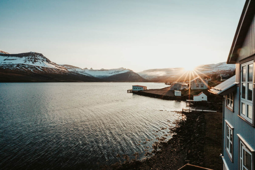 Islandská vesnice u fjordu obklopená zasněženými horami