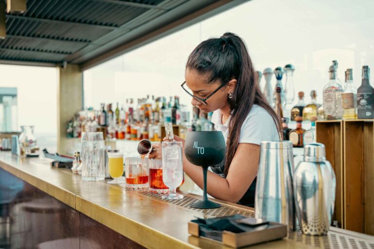 Barmanka připravující koktejly v hotelovém baru na Kypru.