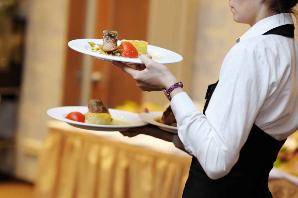 Práce v restauraci, baru nebo kavárně v zahraničí - Servírka nese talíře s jídlem